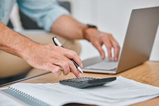 Foto: Männerhände auf PC und Taschenrechner